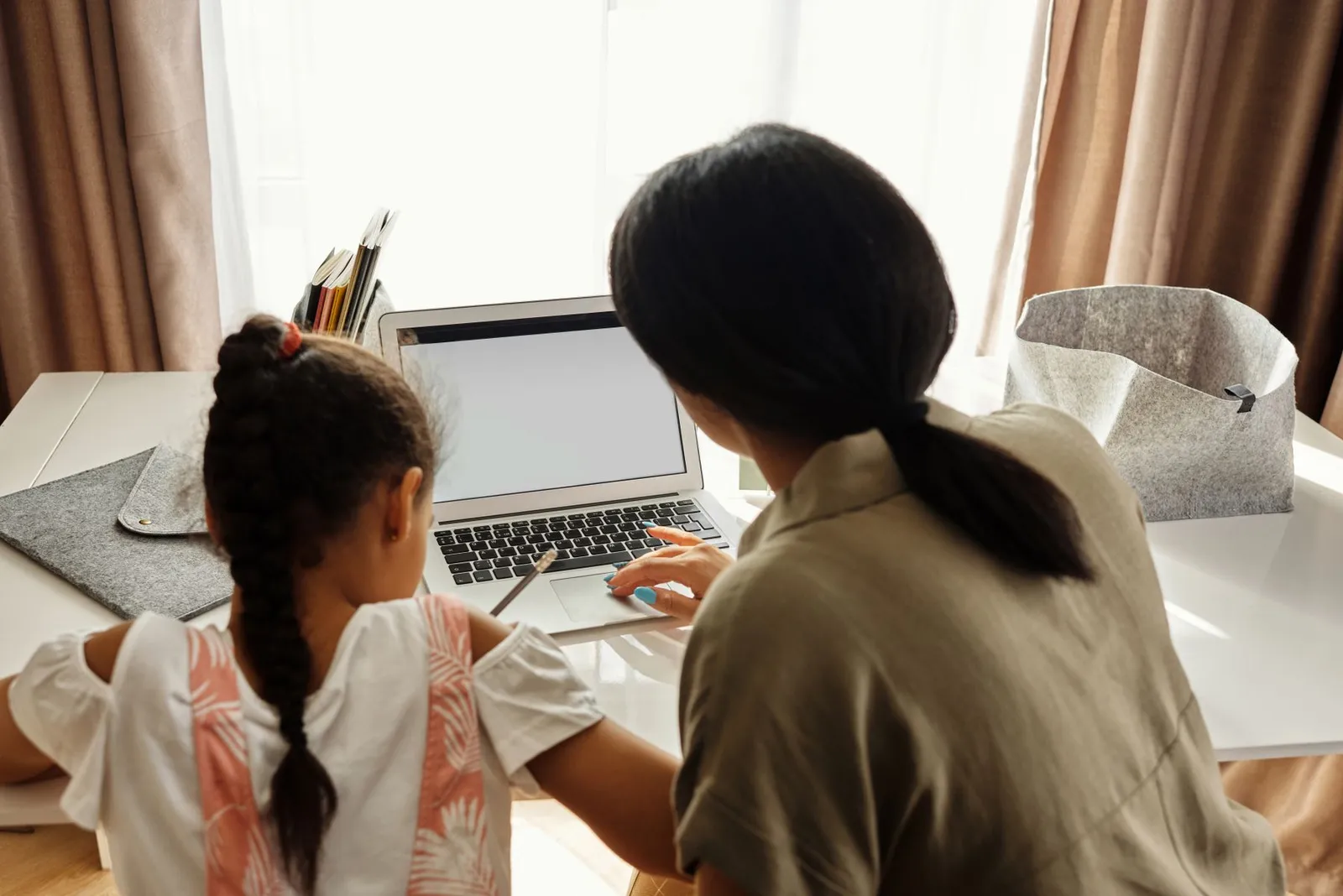 A mentor guiding a young girl through a project on a laptop